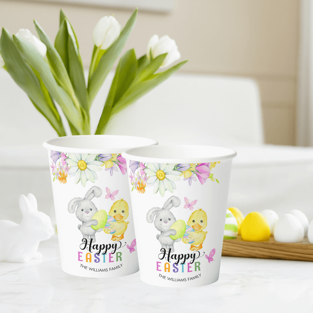 Happy Easter Paper Cups featuring a cute bunny and a chick holding easter eggs surrounded by spring flowers, butterflies and a colorful text.