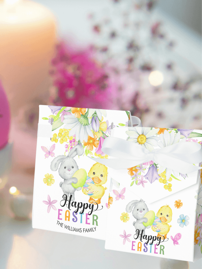 A cute Easter favor box with a white ribbon featuring a cute bunny and a chick holding easter eggs surrounded by spring flowers, butterflies and a colorful text with Happy Easter